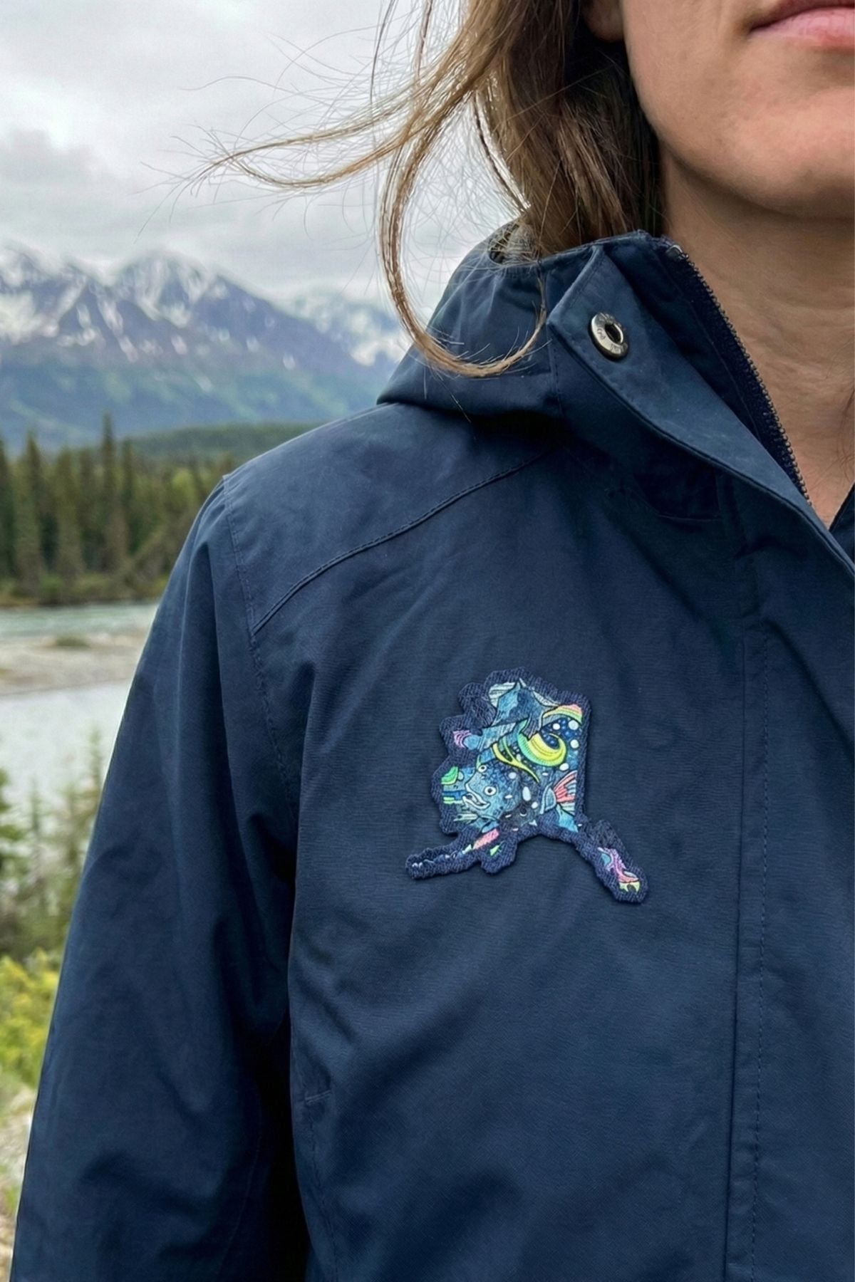 Navy blue jacket with a colorful embroidered design in a mountainous landscape