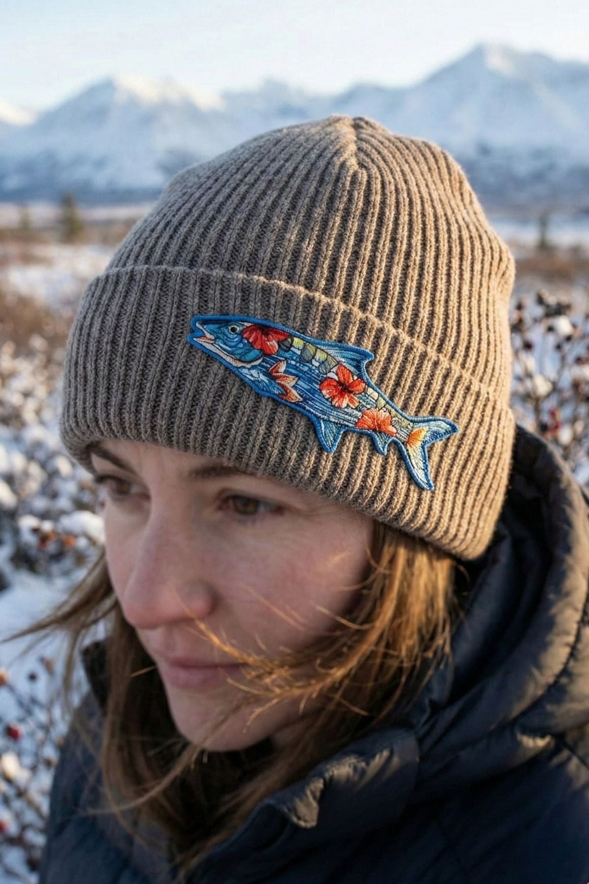 Person wearing a beanie with a fish design in a snowy landscape
