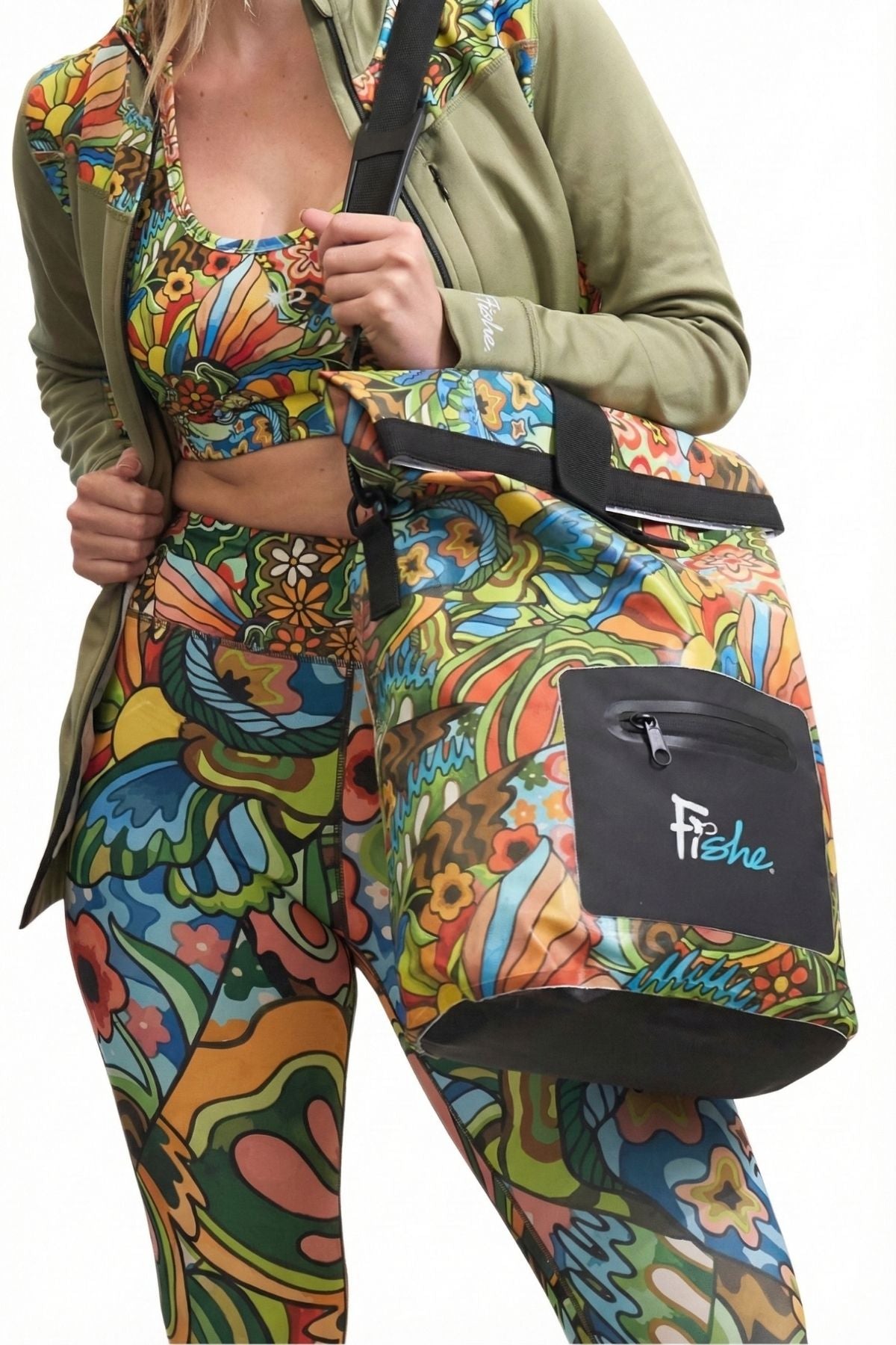 Person wearing colorful floral pants with a matching bag, holding a green jacket.