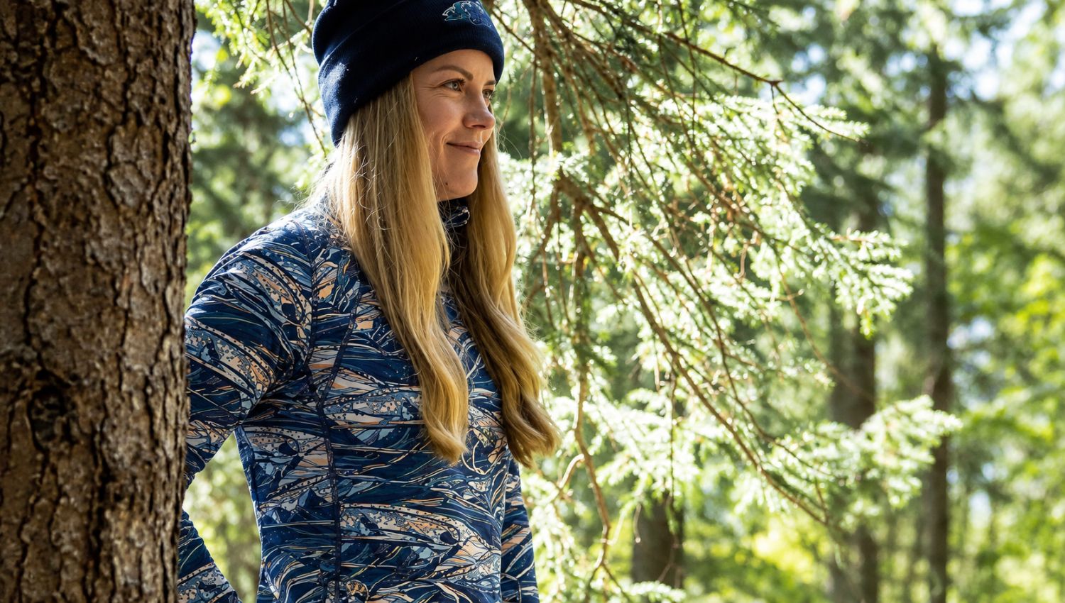 Woman in camouflage jacket and beanie standing in a forest