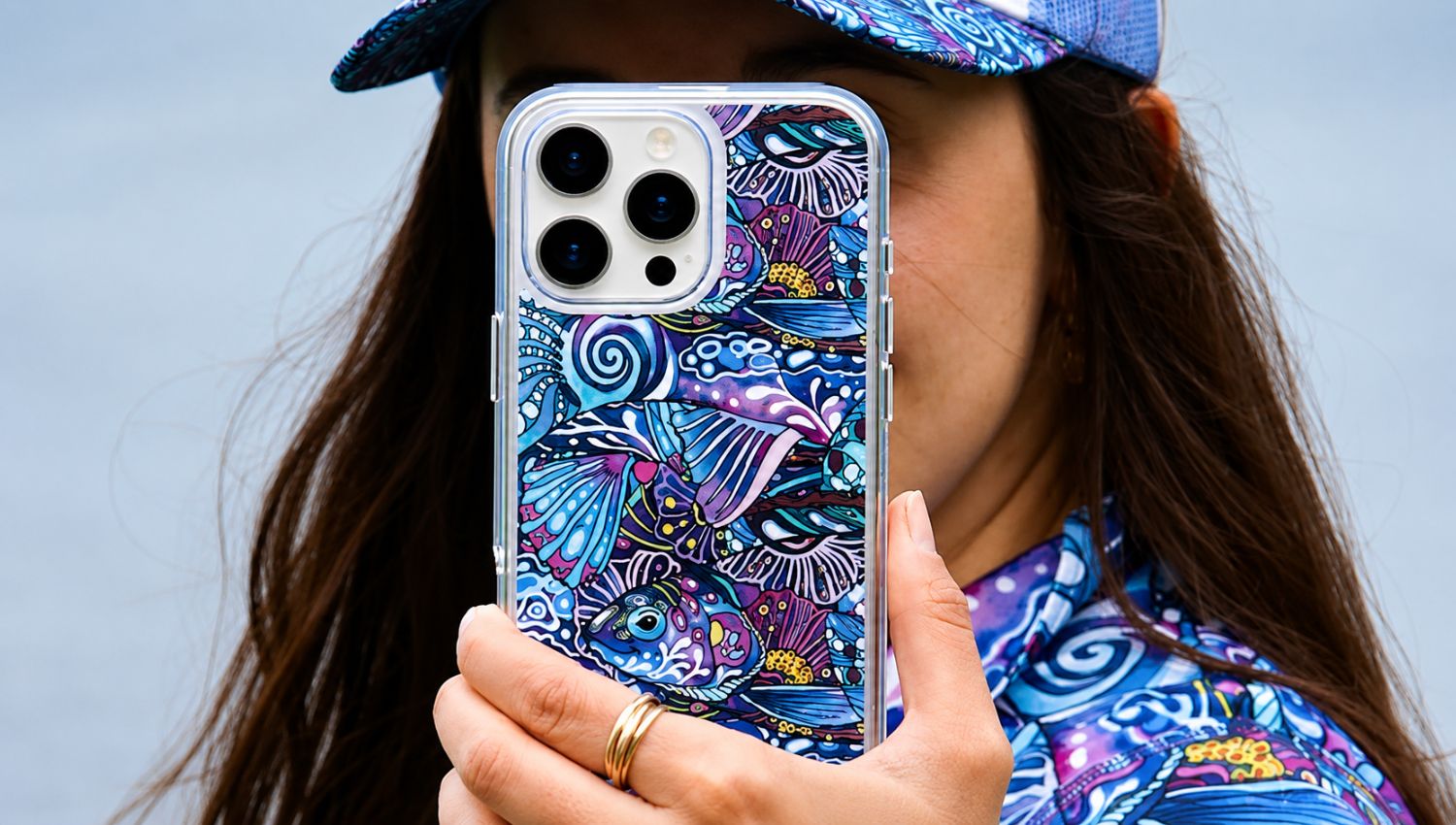 Person holding a phone with a colorful case against a light blue background