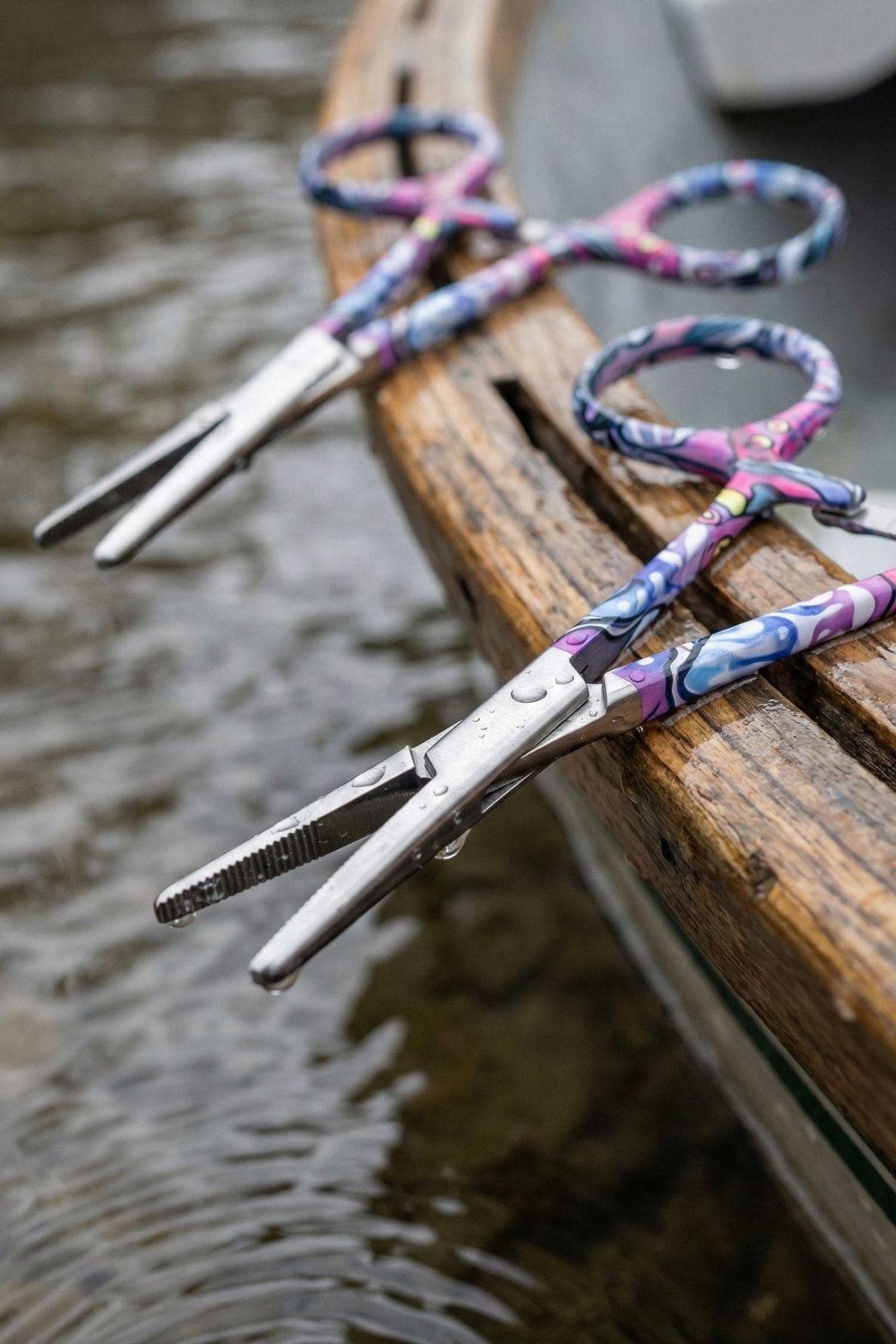 Scissors with colorful handles on a wooden surface near water