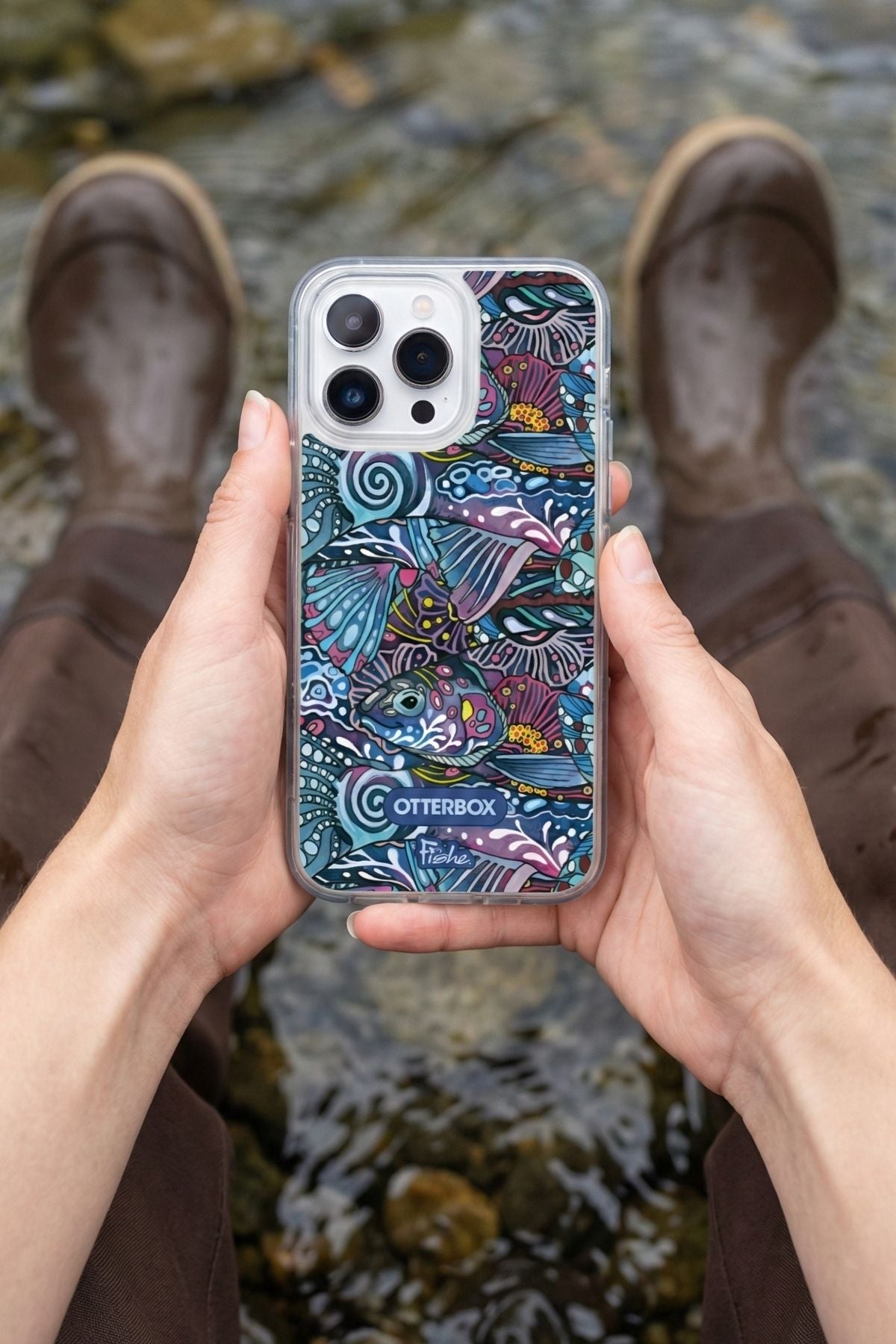 Person holding a phone with a colorful case in front of a water background