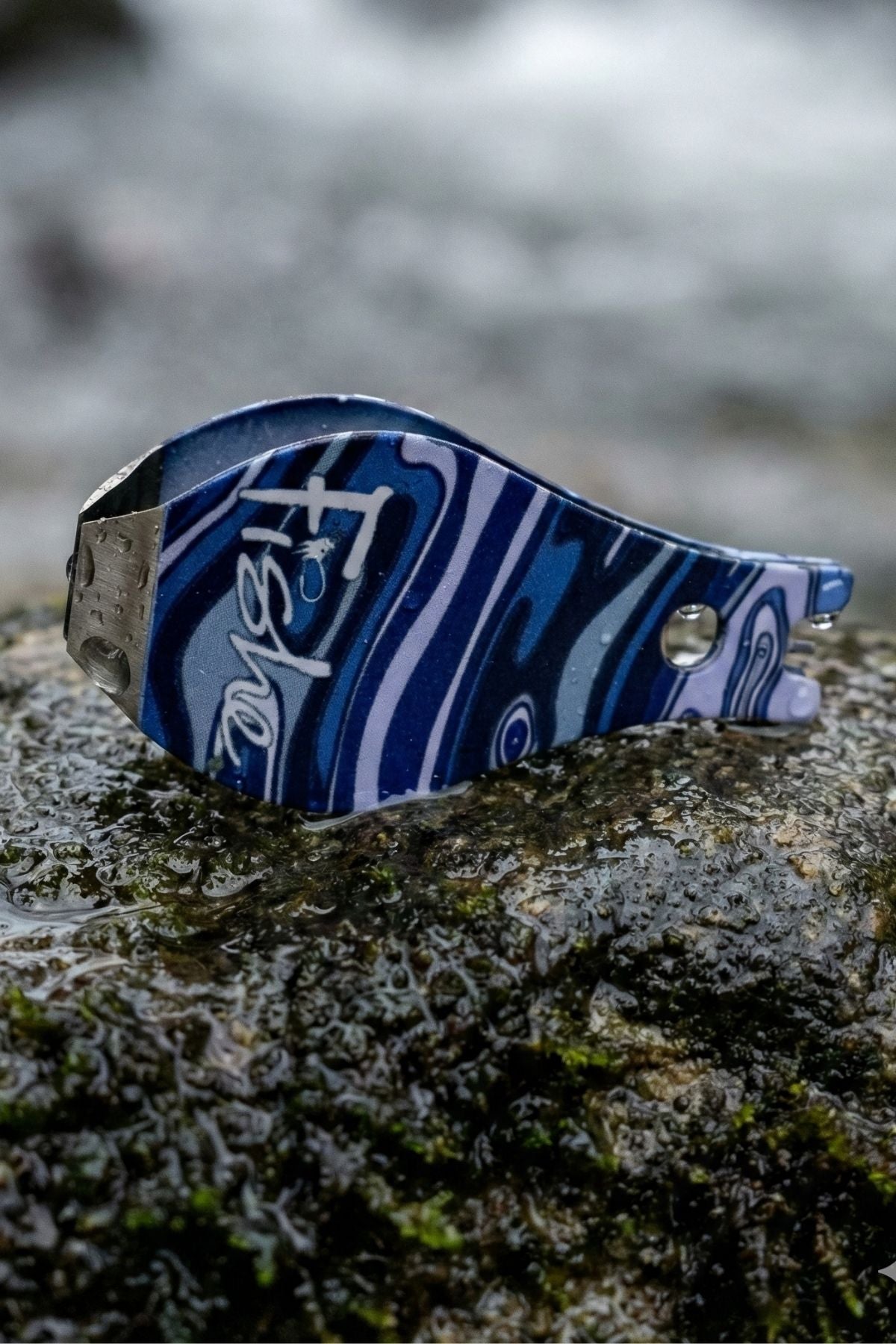 Blue and silver keychain on a textured surface with a blurred natural background