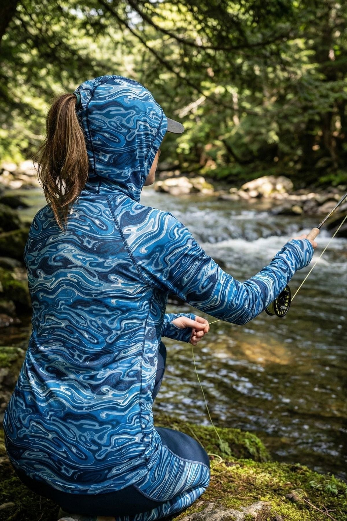 Person wearing a blue patterned jacket by a stream in a forest