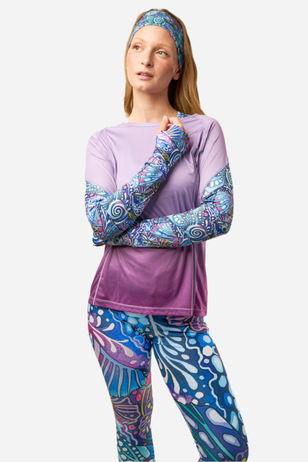Woman wearing a purple long-sleeve top and blue patterned leggings with matching headband on a white background