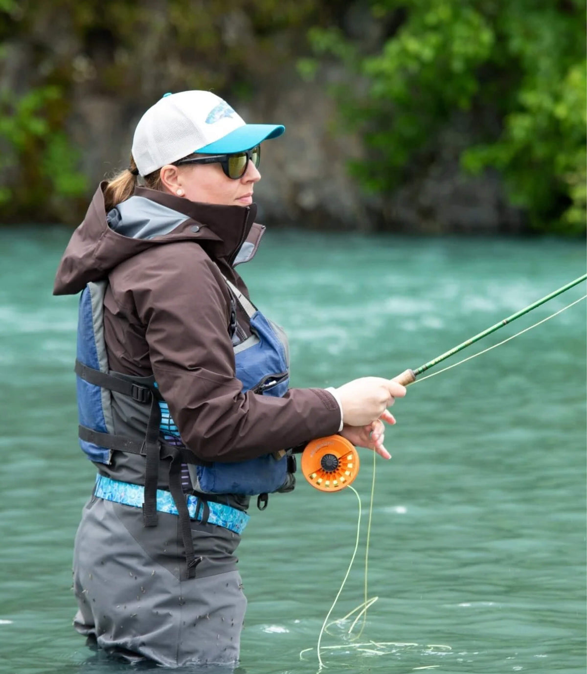 Woman fly fishing in a turquoise river