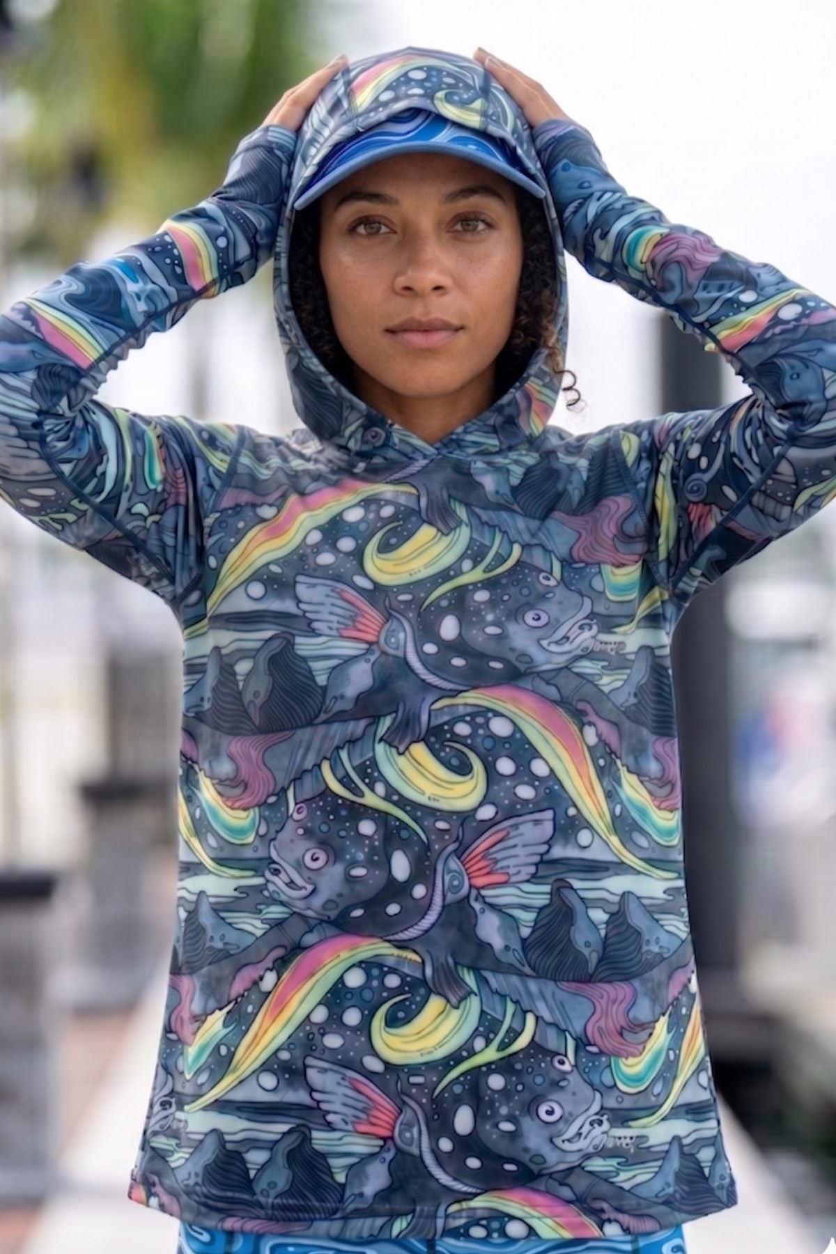 Person wearing a colorful hoodie with fish and wave patterns outdoors