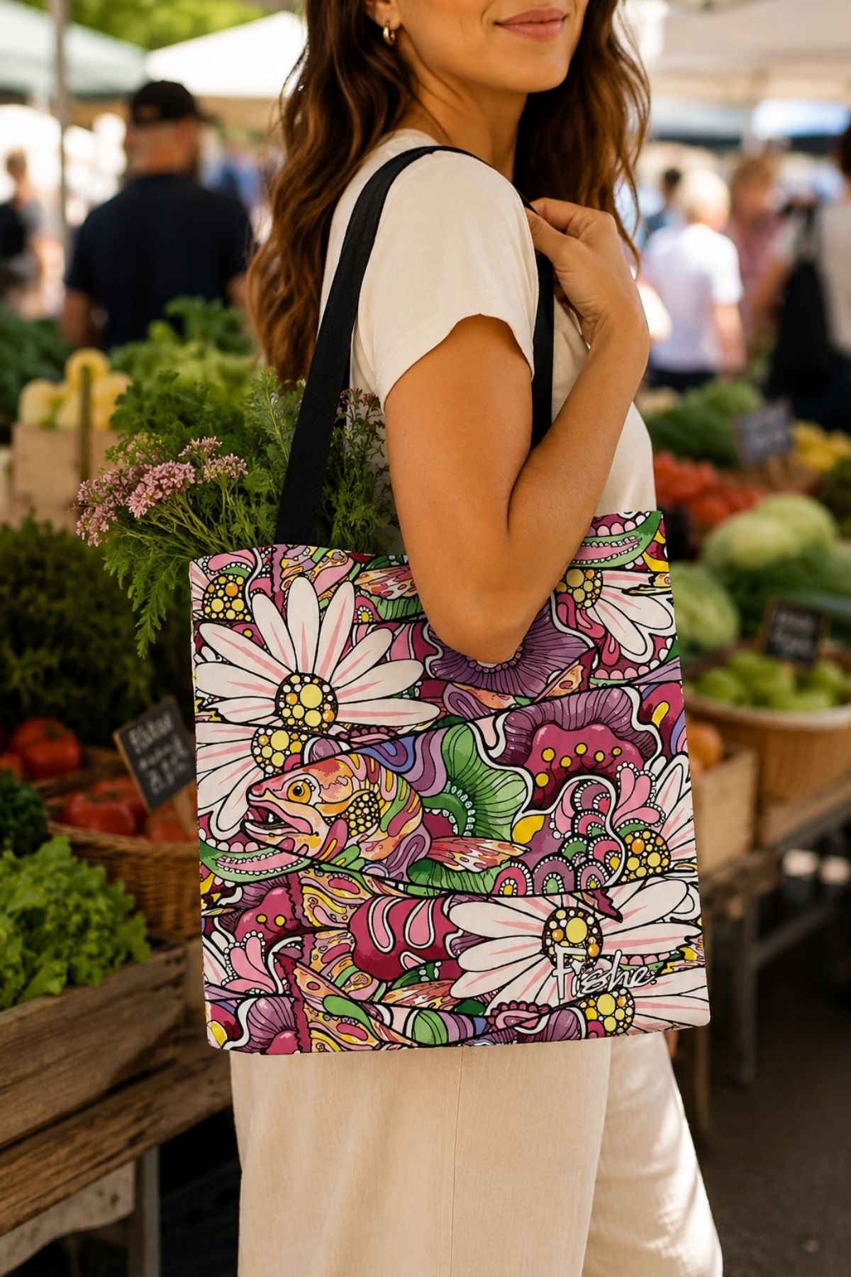 Woman holding a colorful tote bag with floral design at an outdoor market.