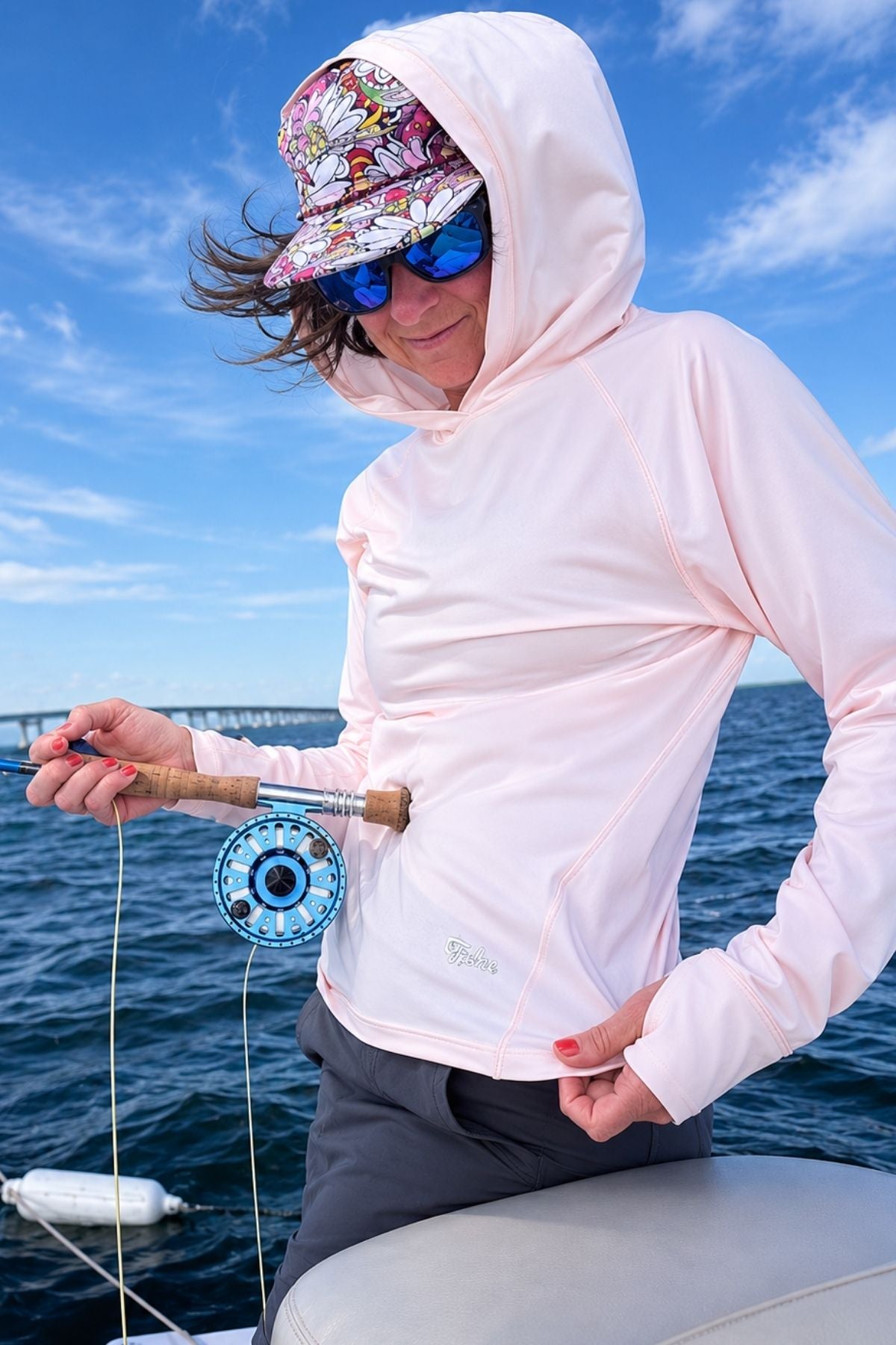 Person on a boat holding a fishing rod with a scenic background