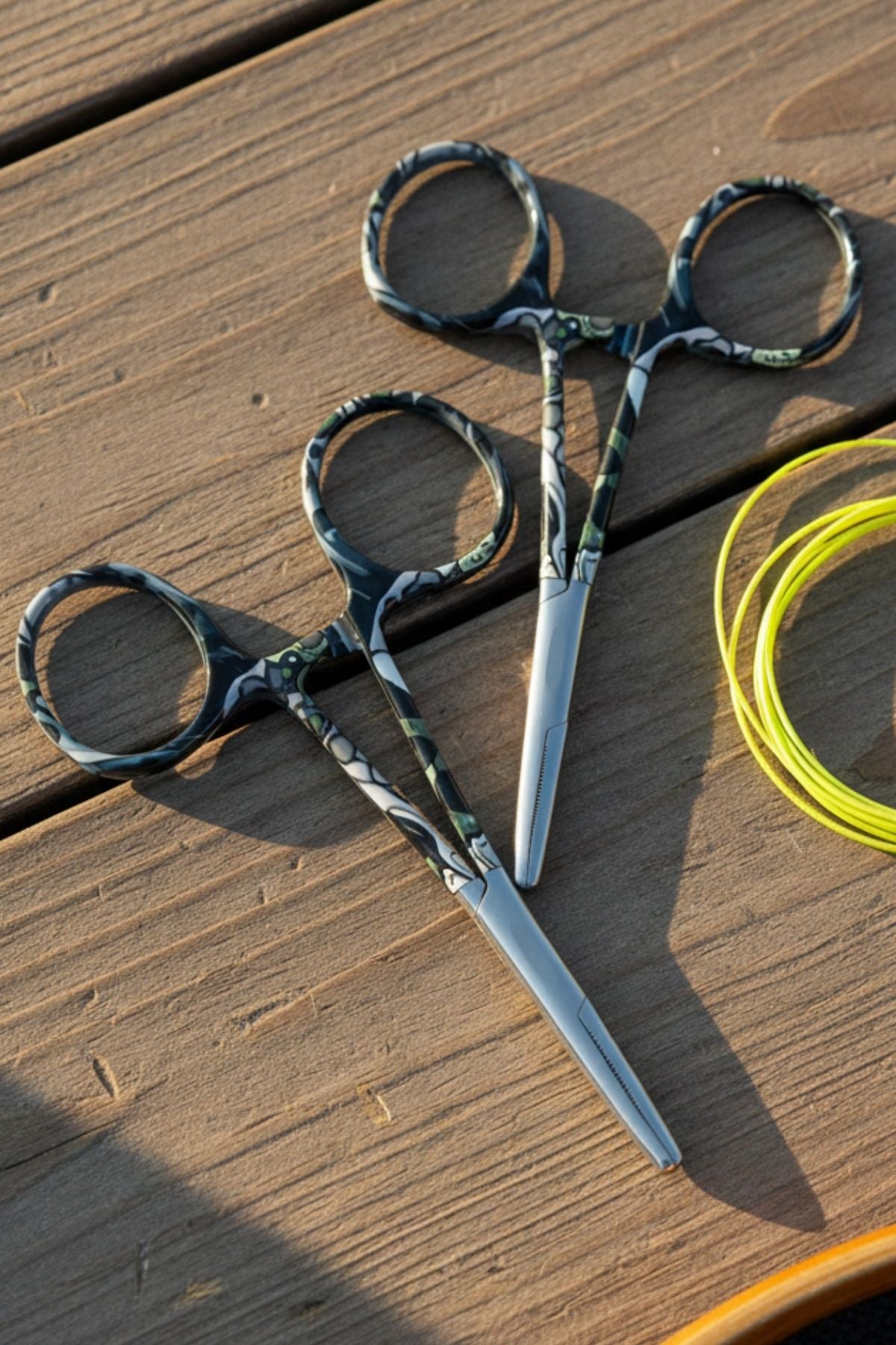 Pair of scissors with camouflage handle on a wooden surface