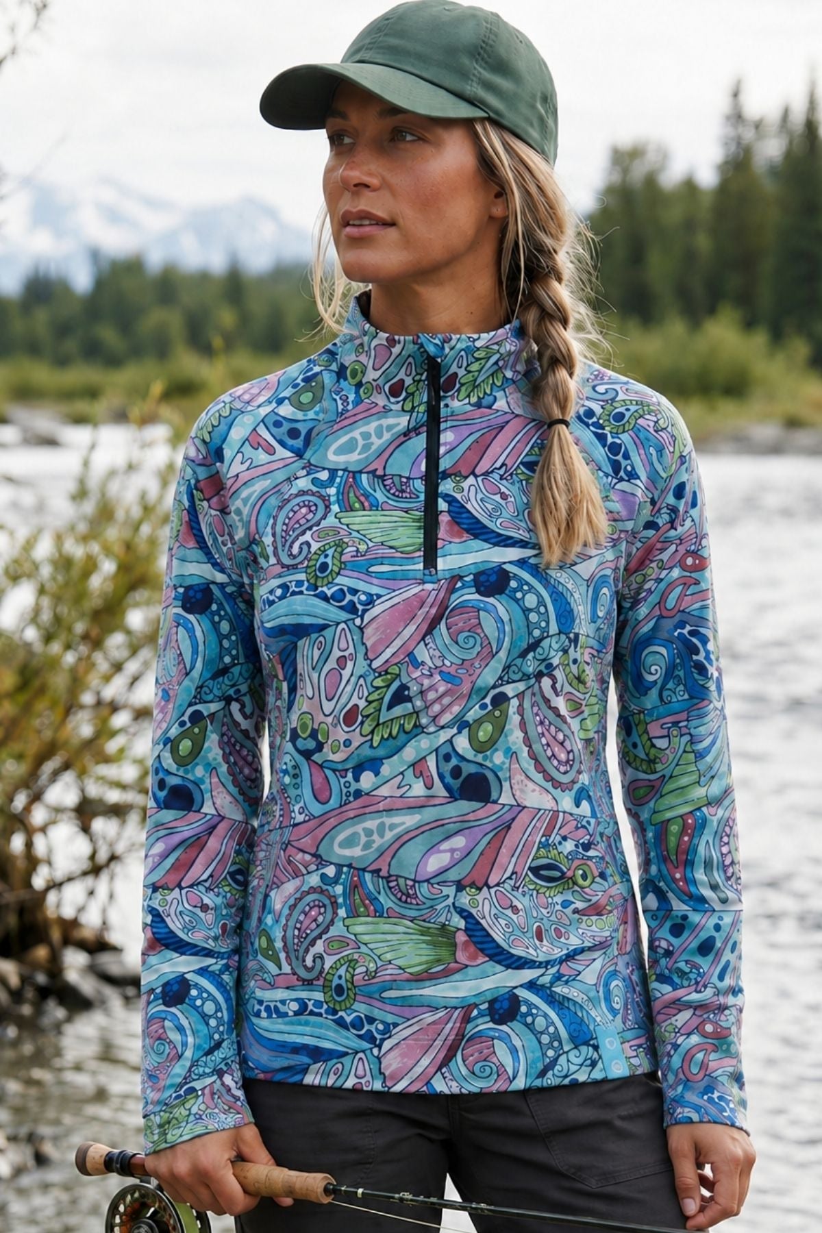 Woman wearing a Radiant Redfish quarter-zip sunshirt beside mountain water
