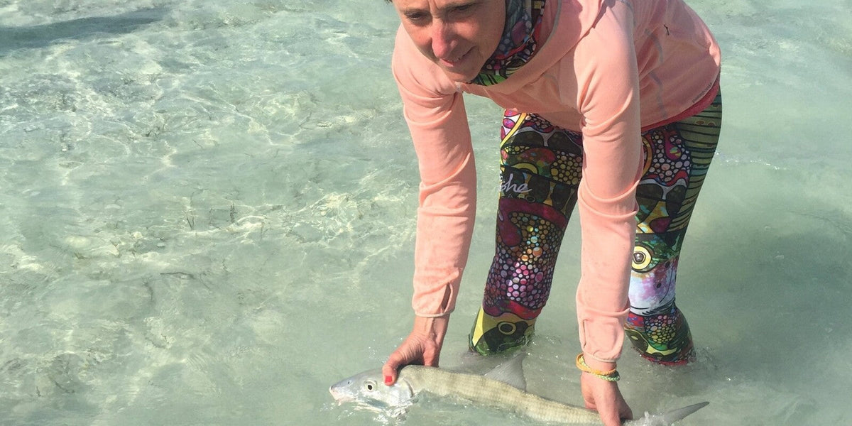 Woman wearing colorful Fishe leggings while flats fishing in tropical saltwater