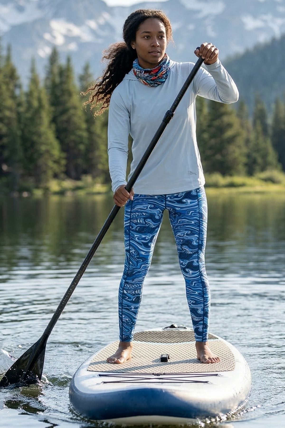 Person paddleboarding on a lake with mountains in the background