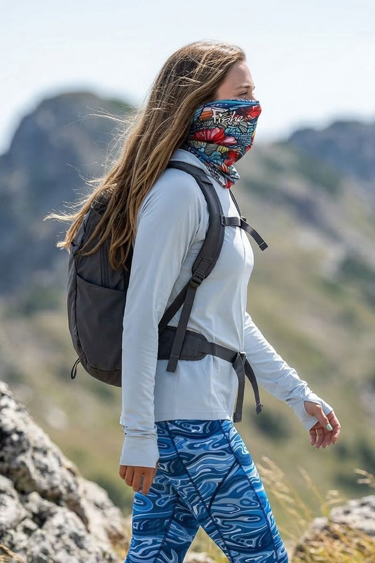 Person hiking with a backpack and colorful bandana in a mountainous area