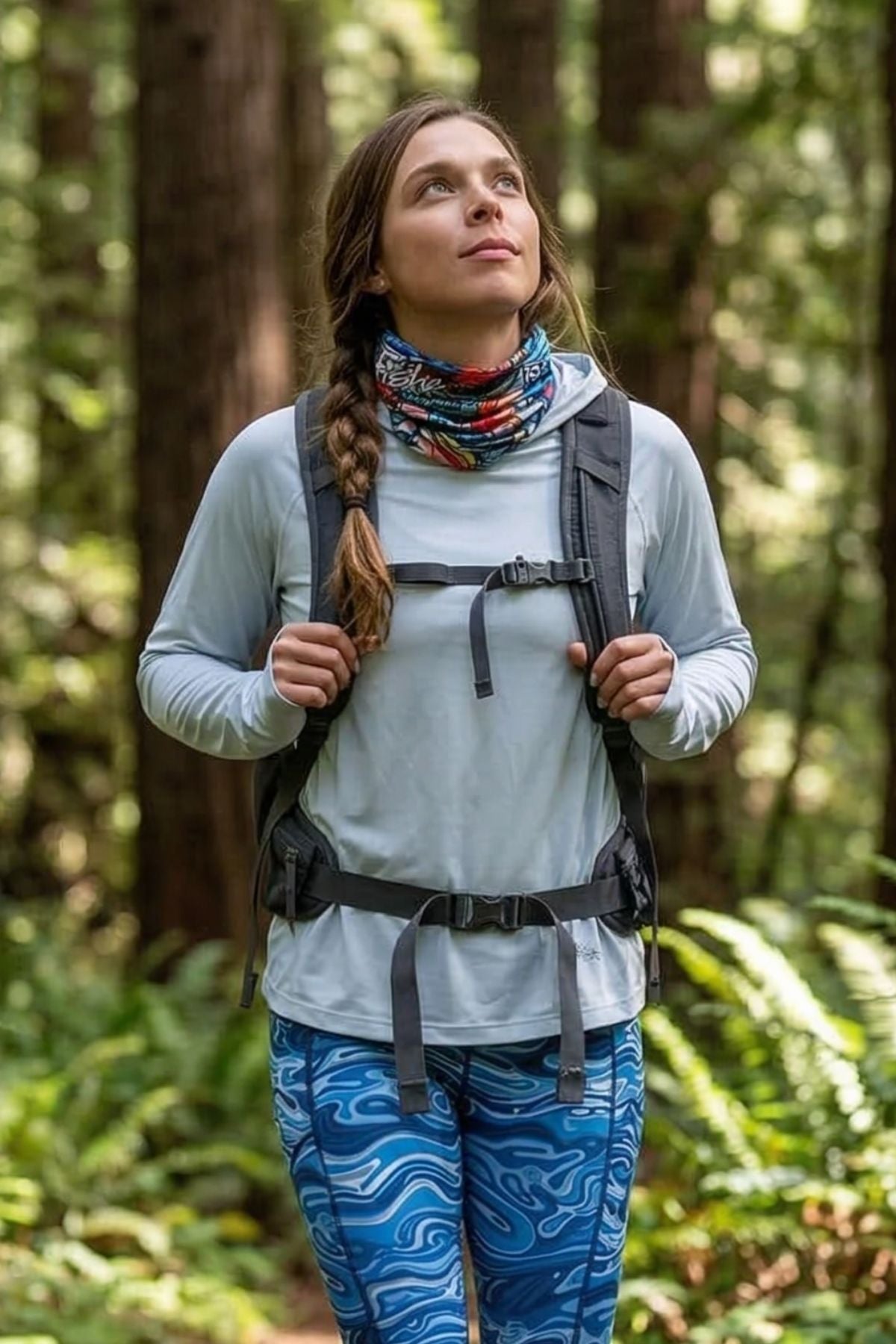 Woman hiking in a forest wearing a backpack and colorful pants.