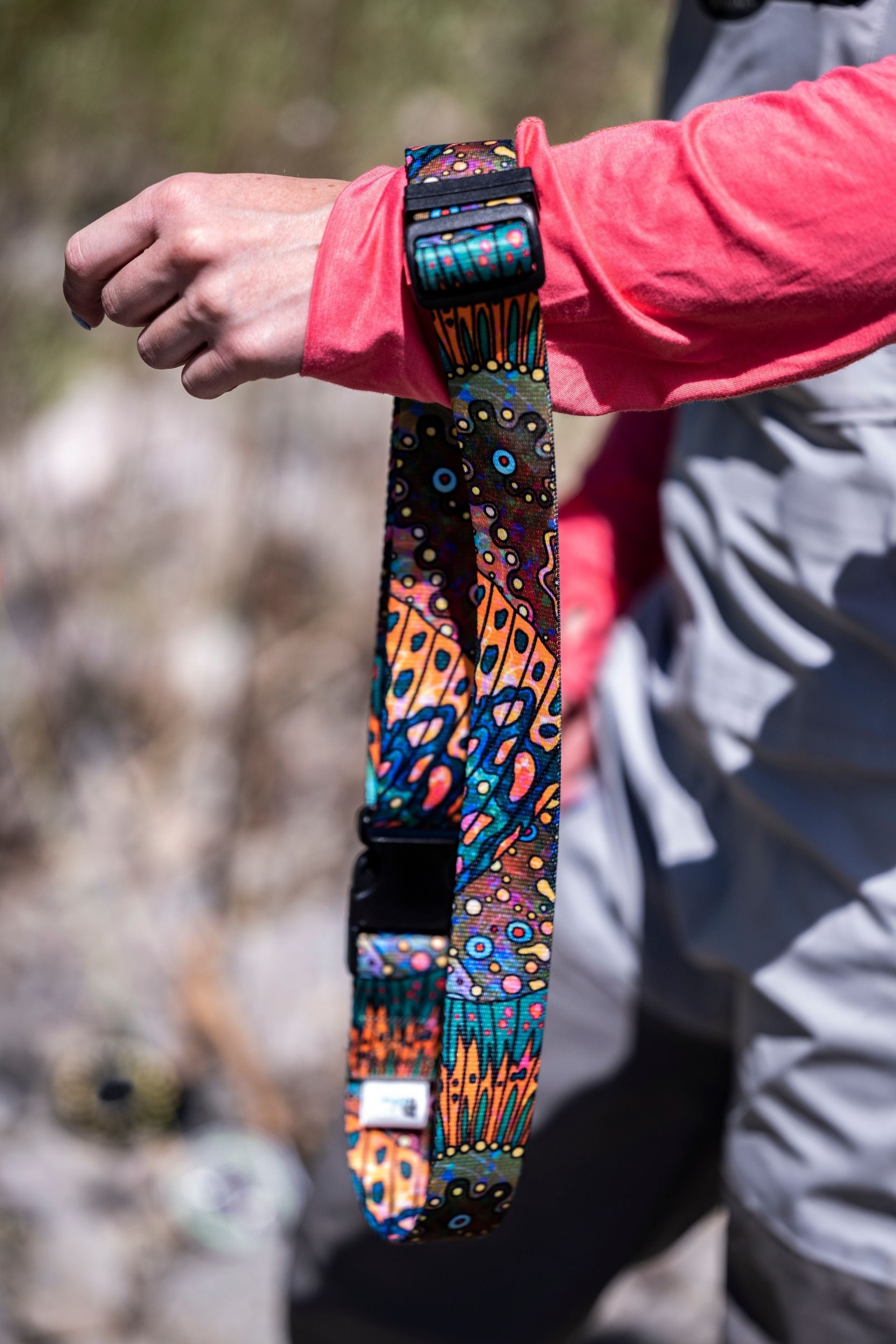 Colorful dog collar with intricate patterns held by a person outdoors.