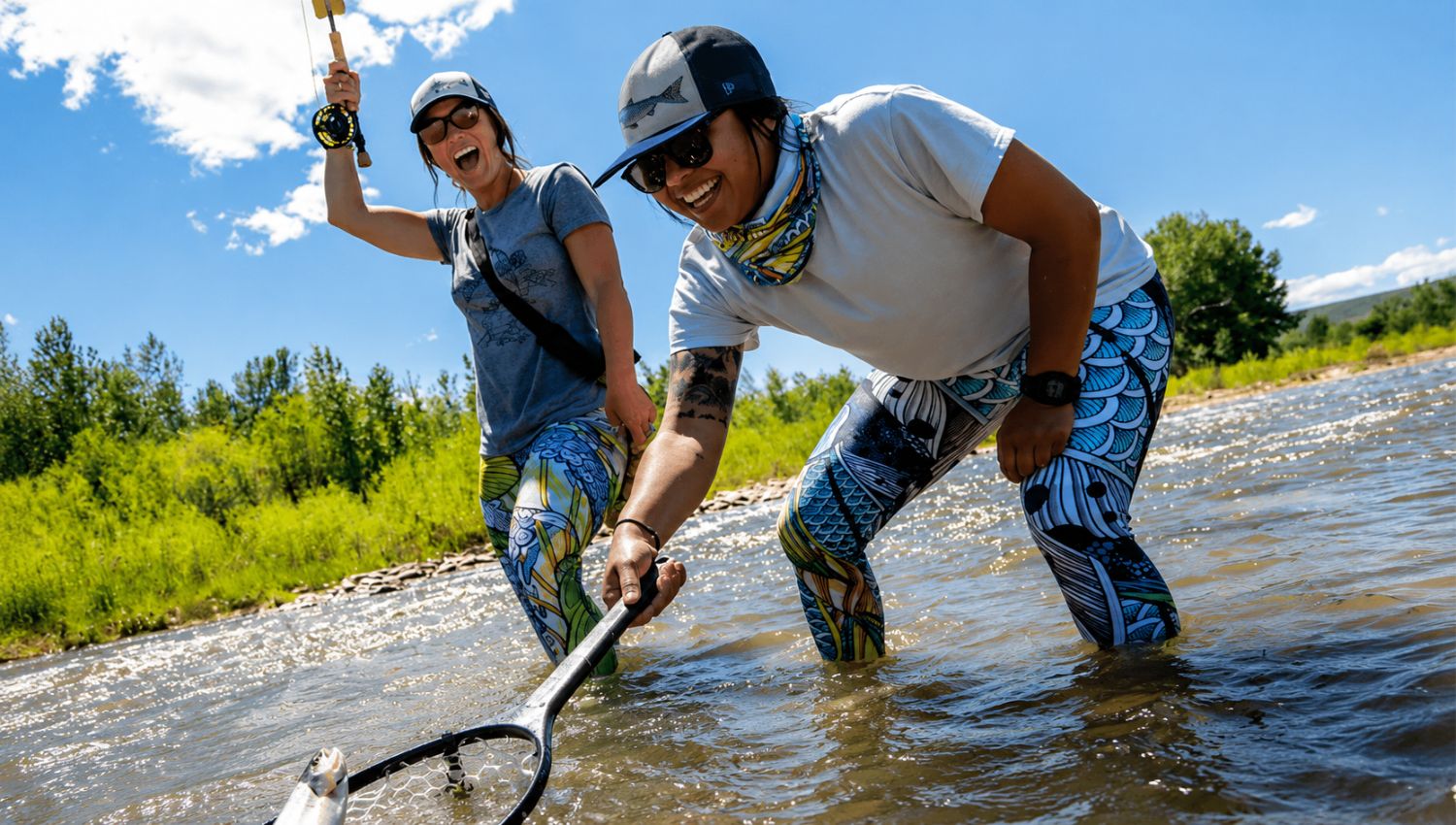 Two people wading through water with fishing nets on a sunny day.