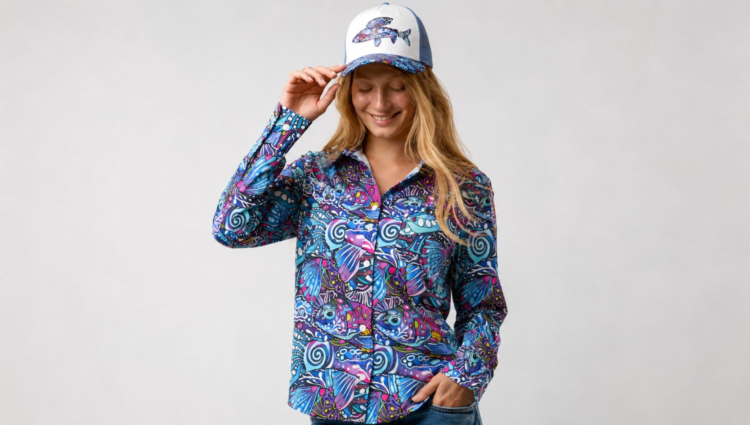 Woman wearing a colorful patterned shirt and cap on a plain background
