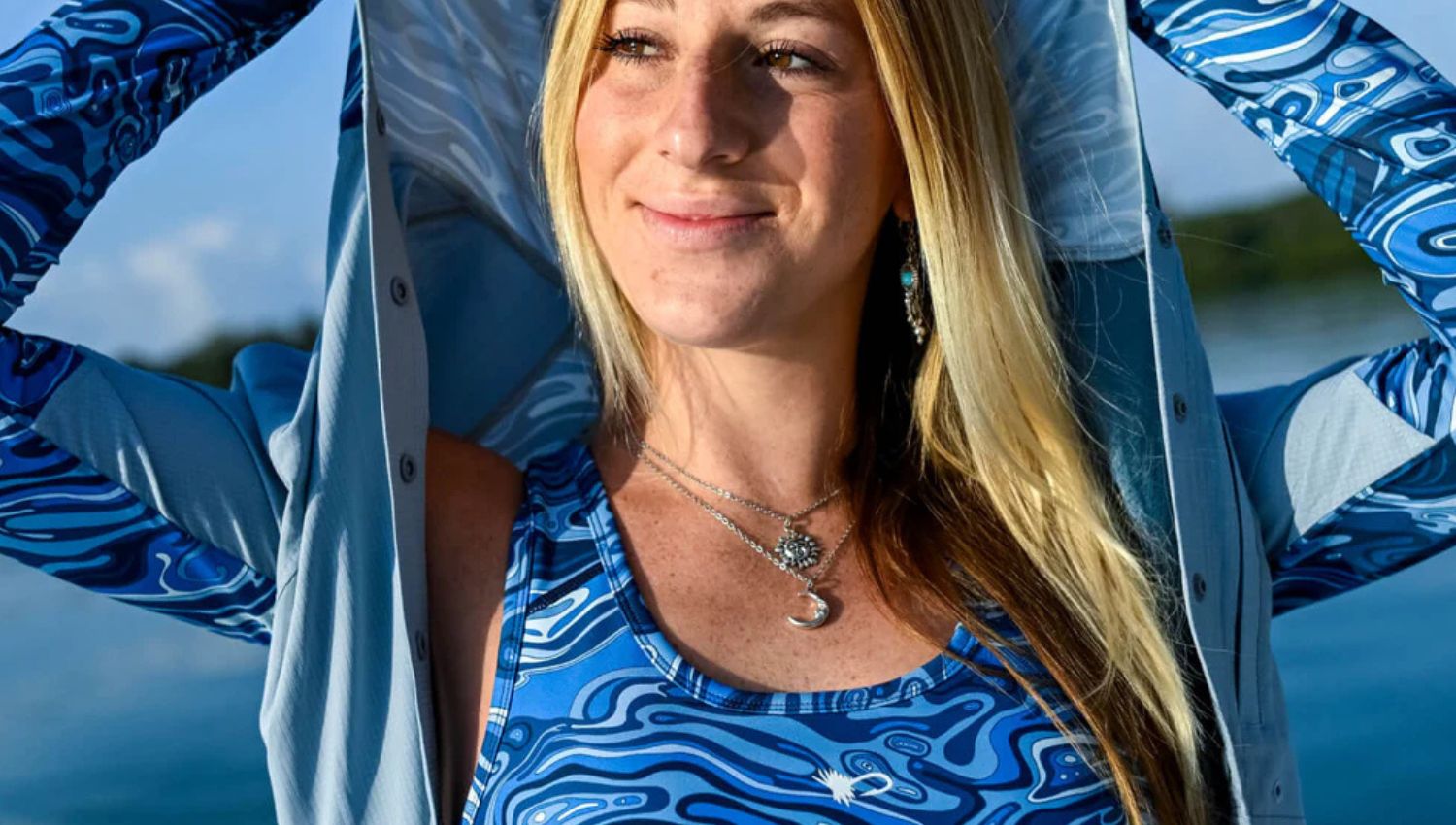 Woman wearing a blue patterned top with a hooded jacket outdoors