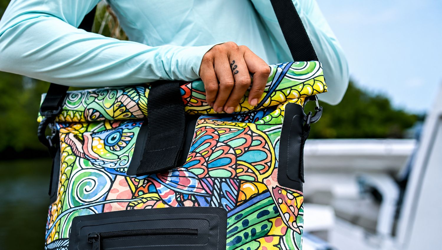 Colorful patterned bag held by a person with a blurred outdoor background