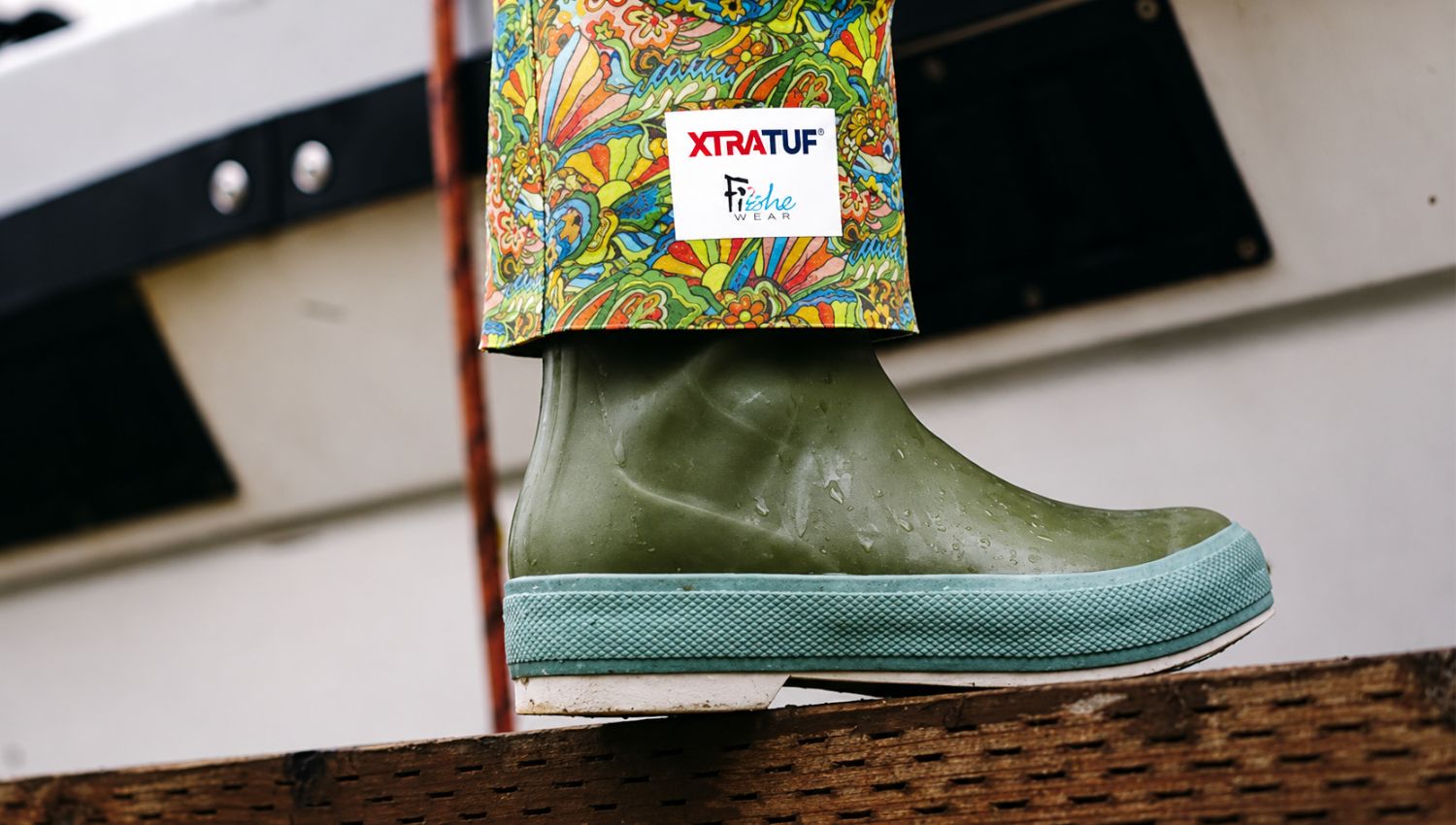 Green rubber boot with colorful patterned legging and Xtratuf logo on a white background