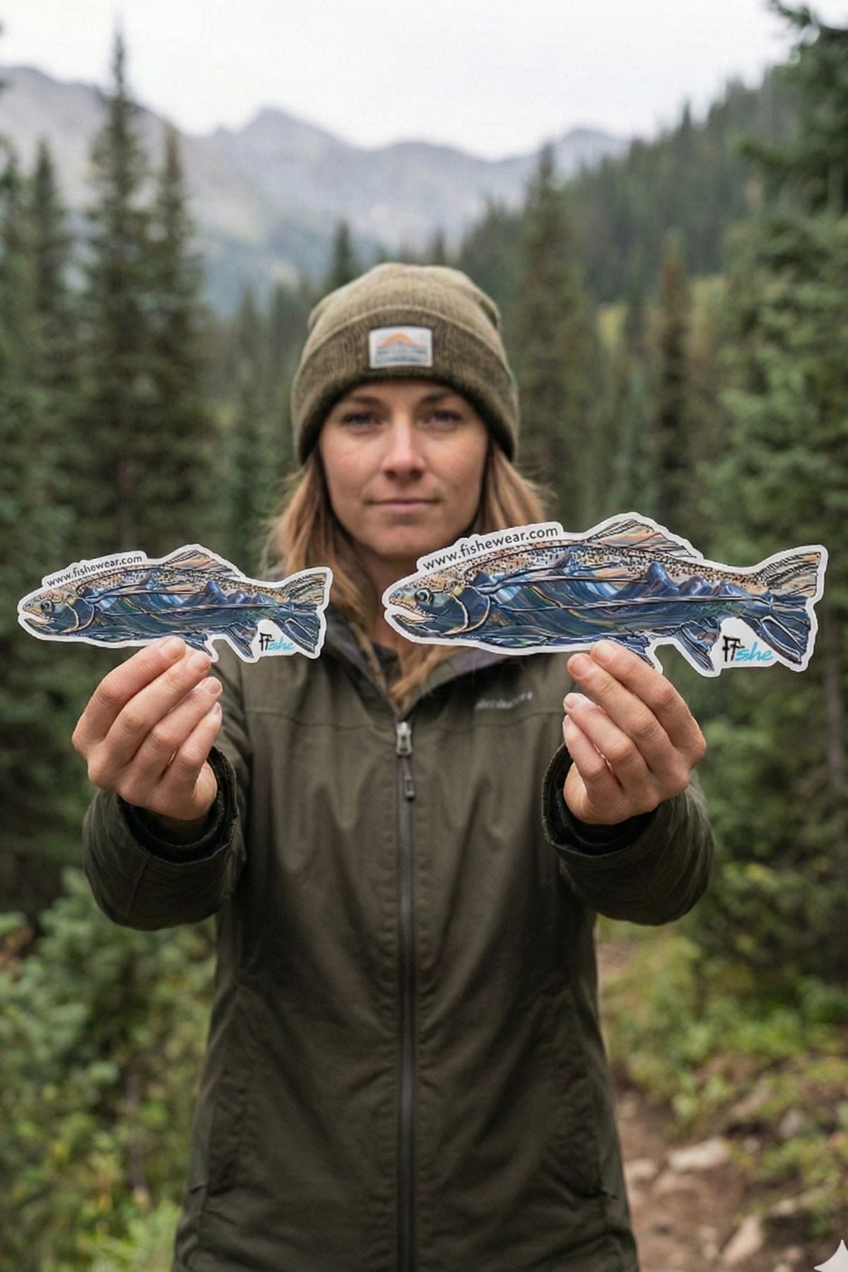 Person holding two paper cutouts of fish in a forest setting