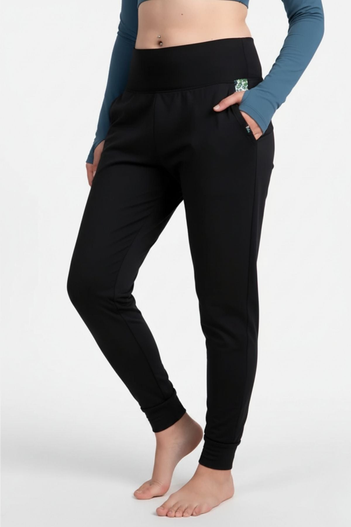 Person wearing black jogger pants with a blue long-sleeve top on a white background