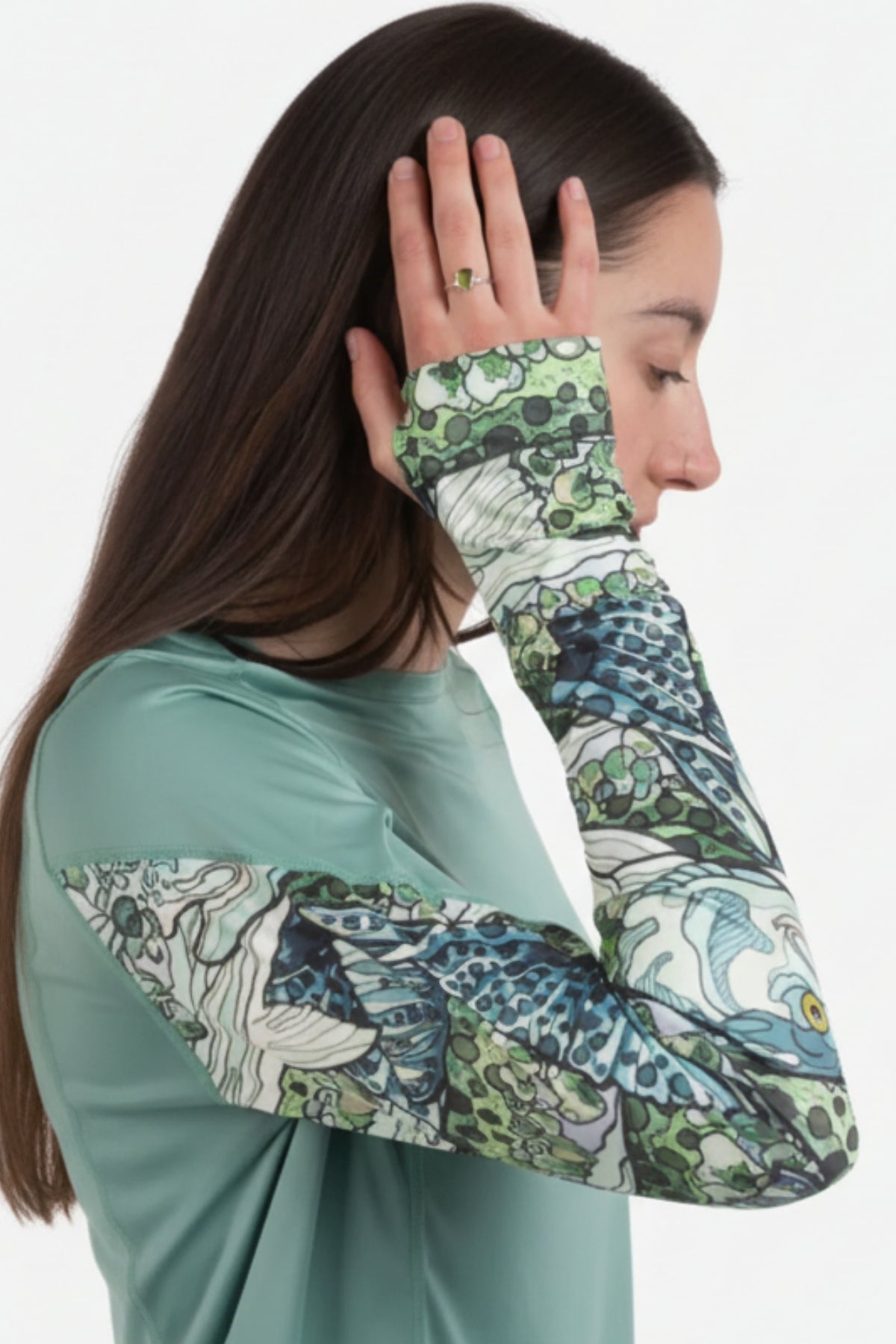 Person wearing a green long-sleeve shirt with floral patterned sleeves on a white background