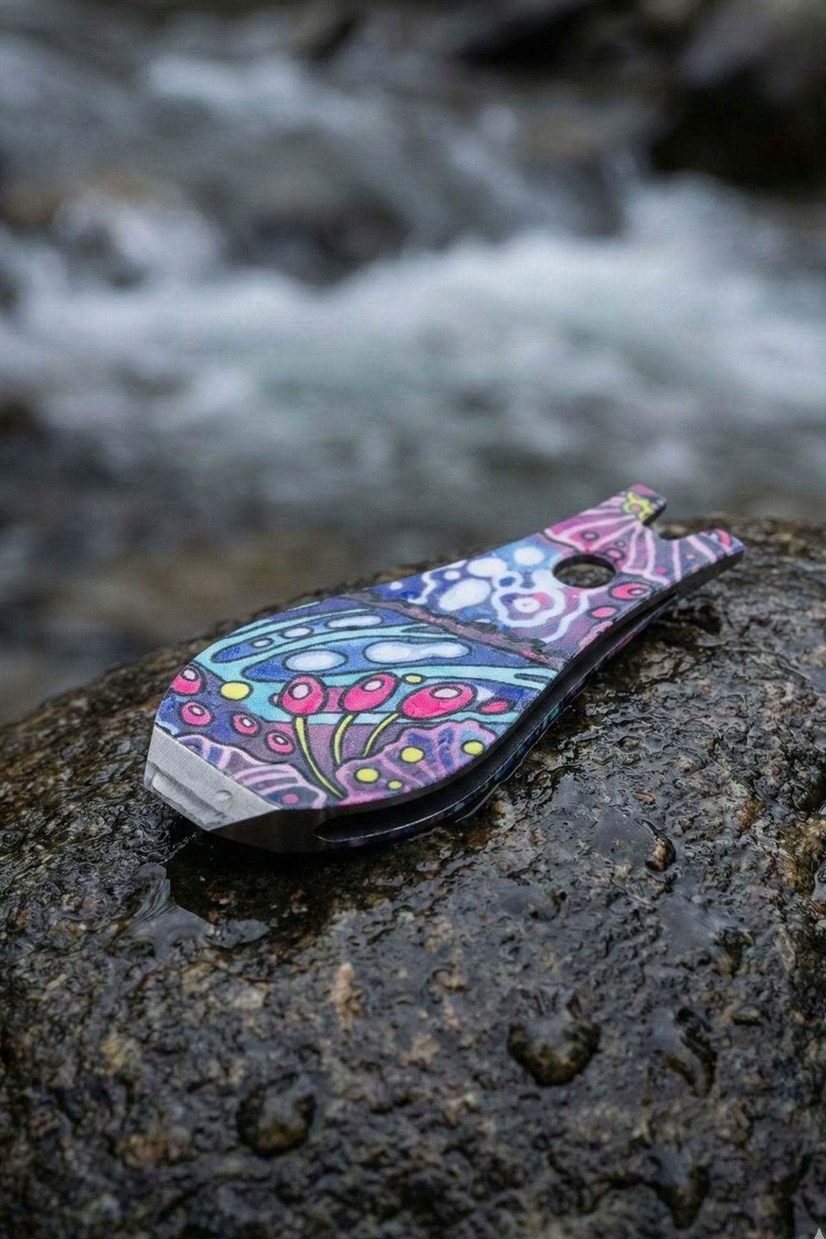 Colorful butterfly-shaped keychain on a rock with water in the background