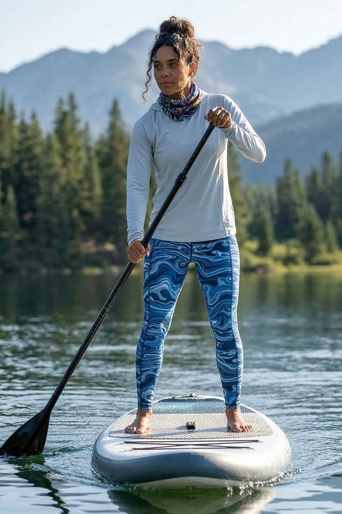 Person paddleboarding on a lake with mountains and trees in the background