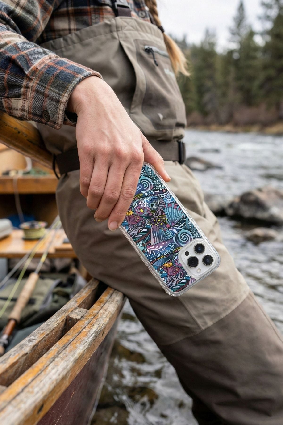 Person holding a phone with a colorful case by a river