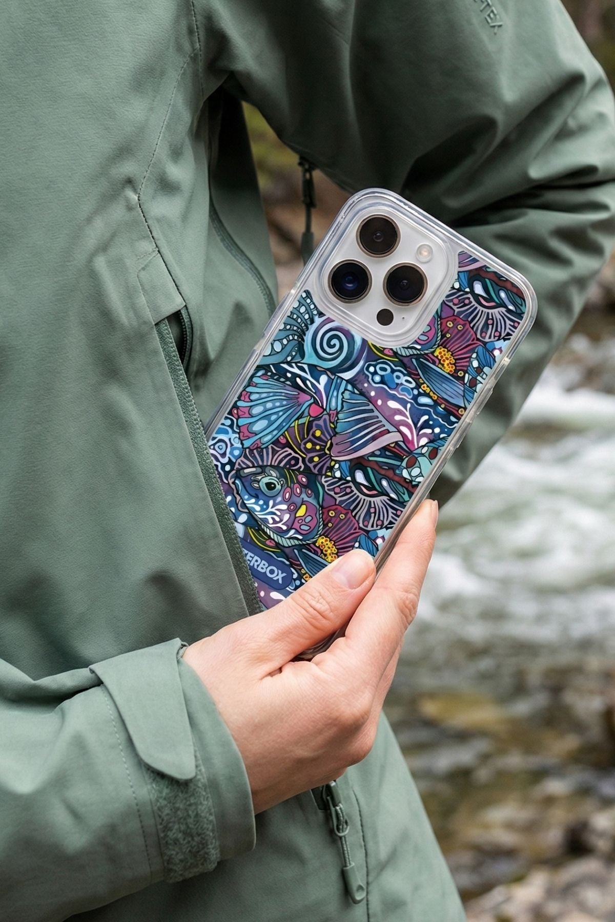 Person holding a phone with a colorful case outdoors