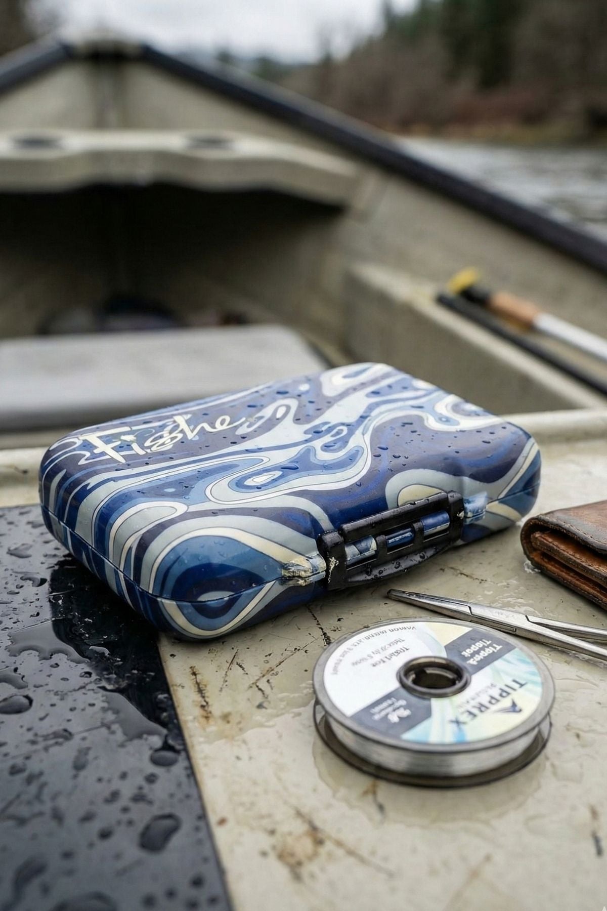 Blue and white patterned fishing reel case on a boat deck with fishing line and tools.
