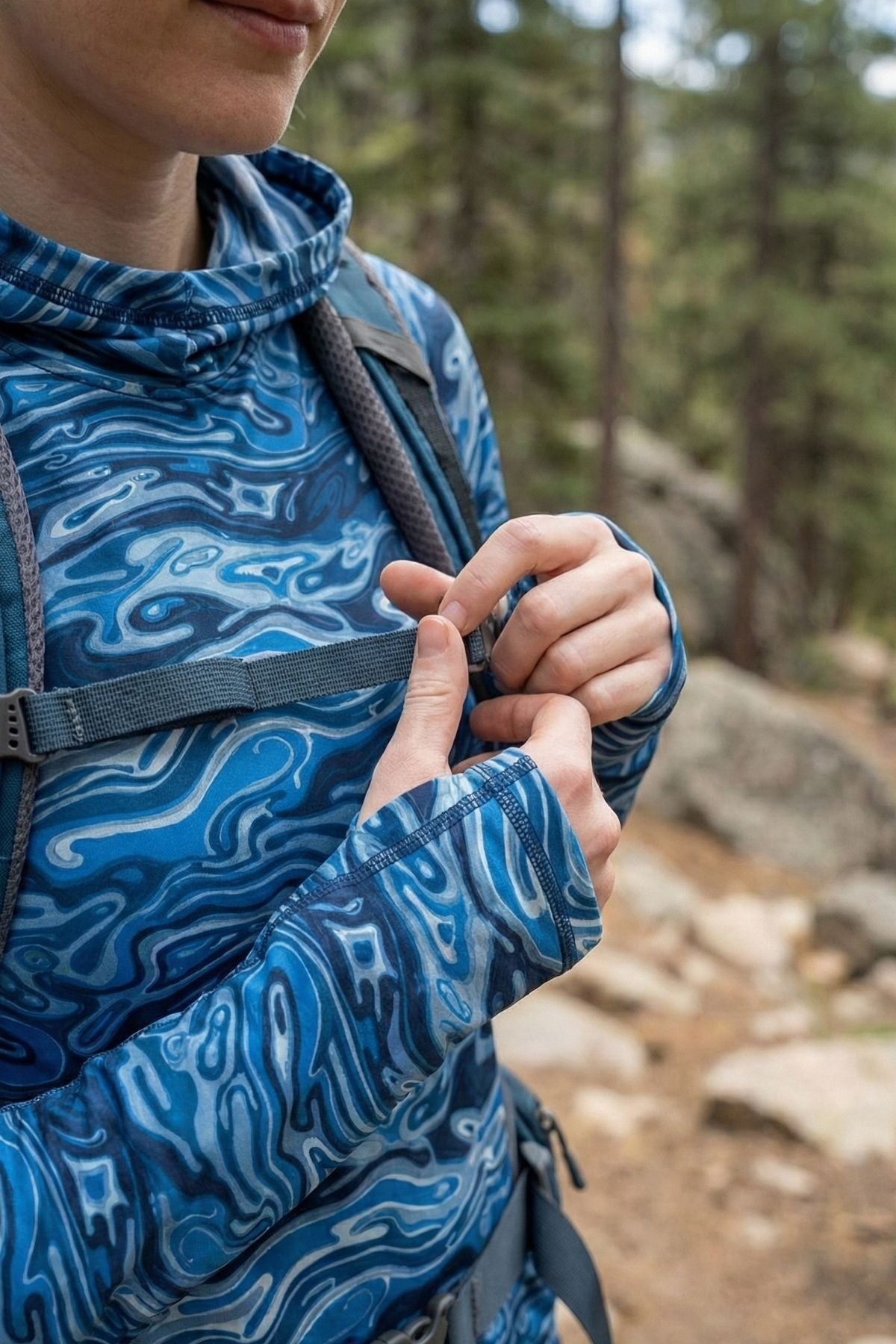 Person wearing a blue patterned jacket with a backpack outdoors on a trail.