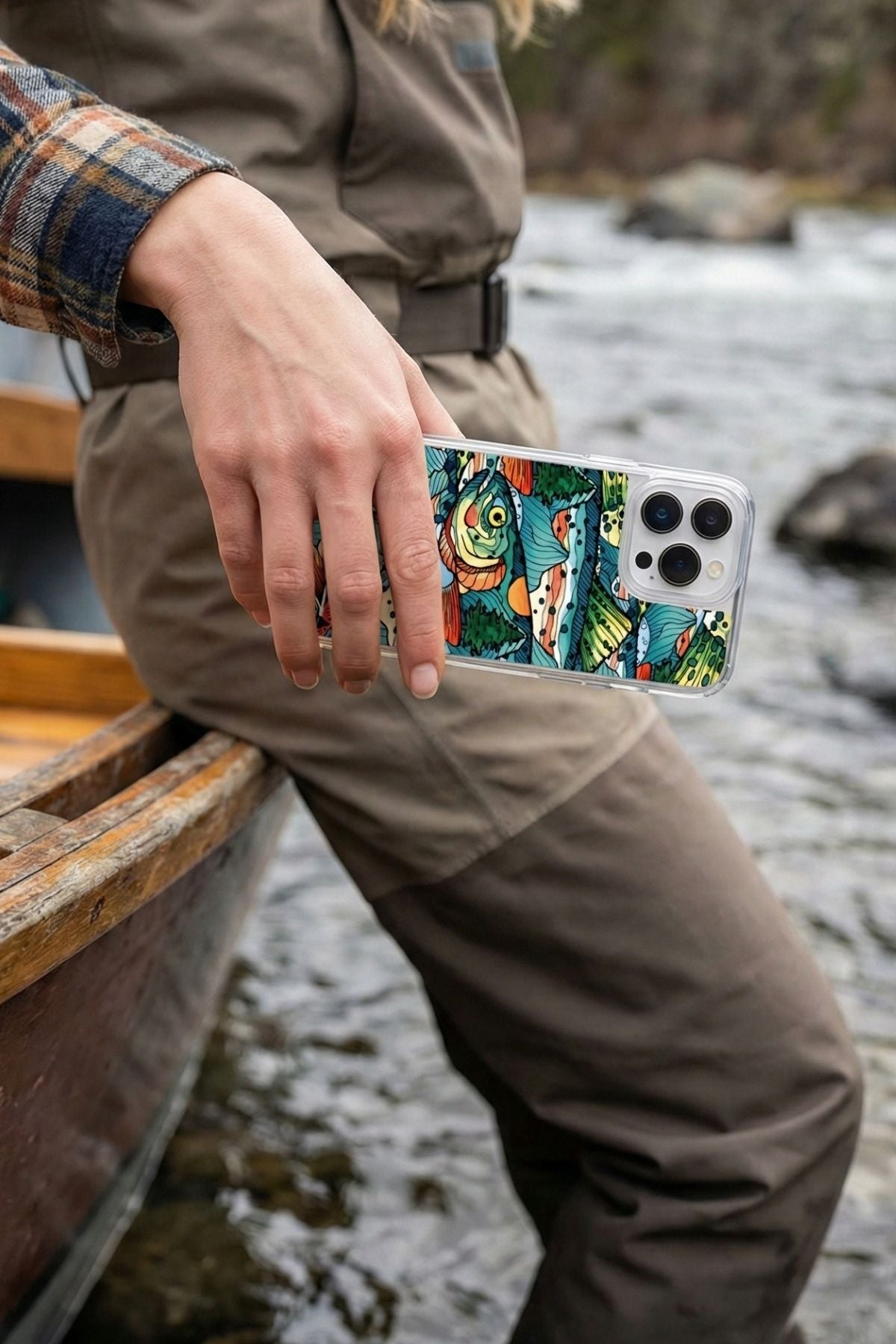 Person holding a phone with a colorful case by a river