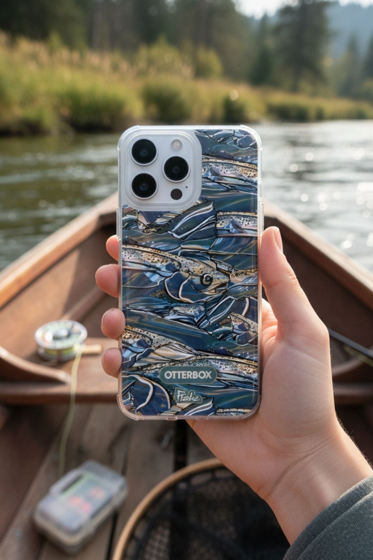 Person holding a phone with a fishing-themed case by a lake