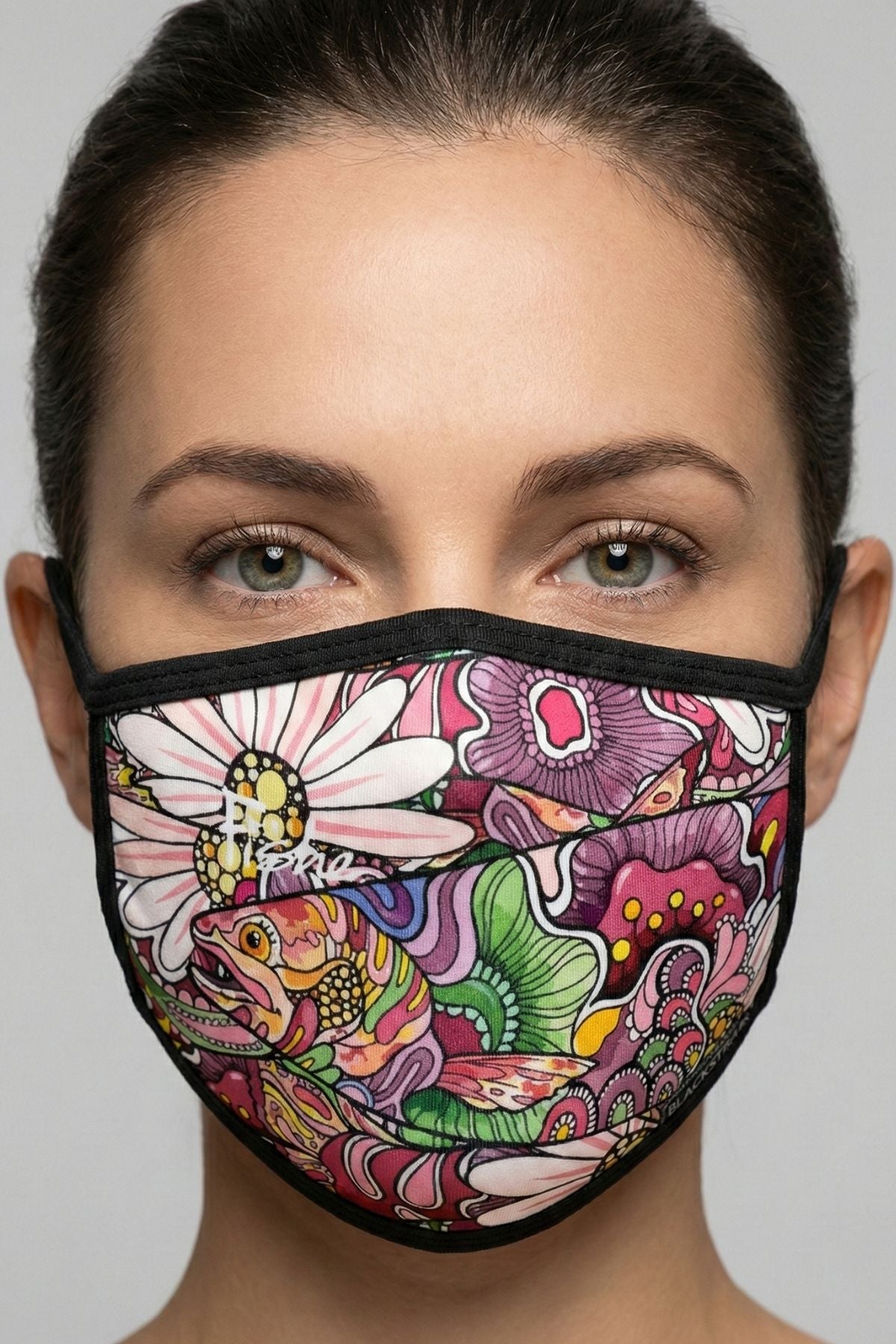 Person wearing a colorful face mask with floral and abstract designs on a gray background
