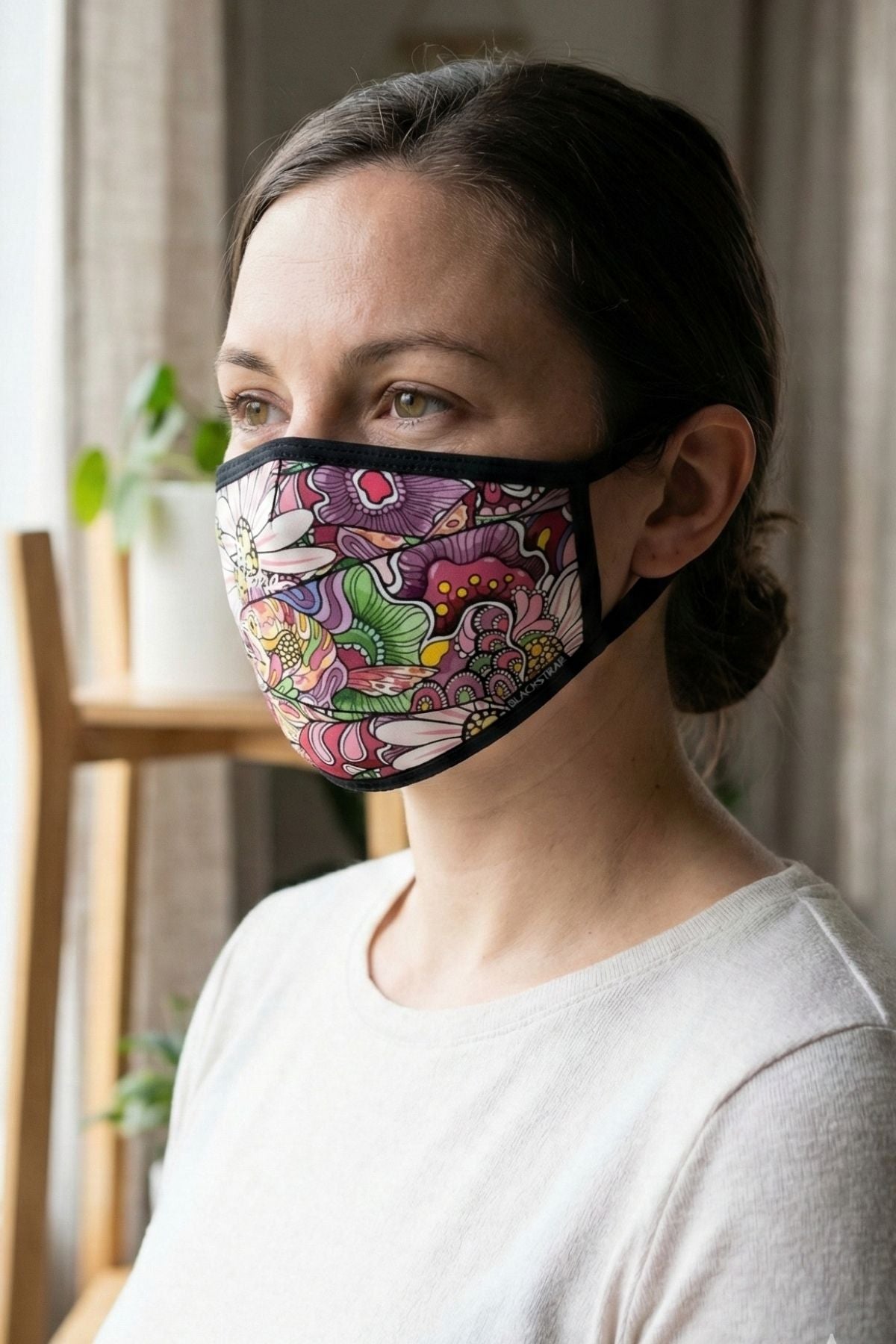 Woman wearing a colorful patterned face mask indoors
