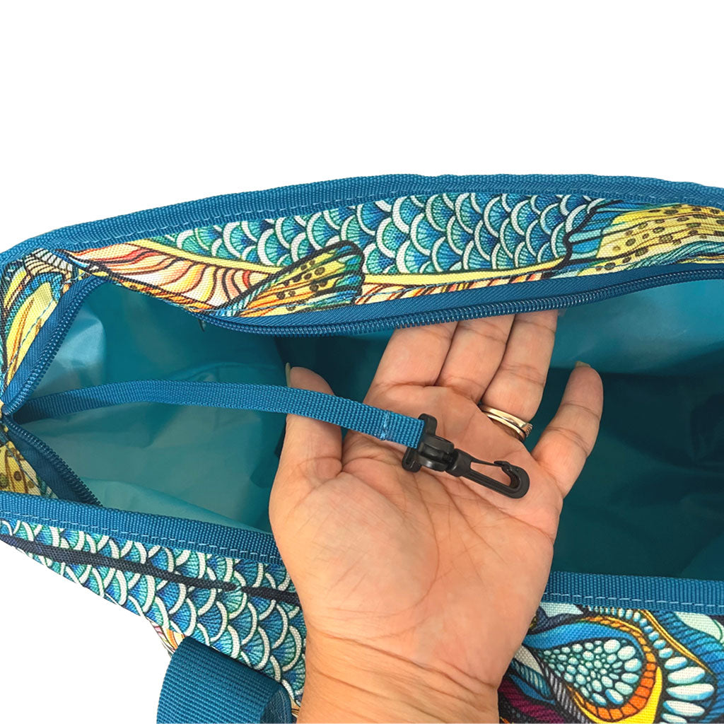 A hand inside the Kaleido King Weekender Bag holding a plastic clip that attaches to the inside of the bag.